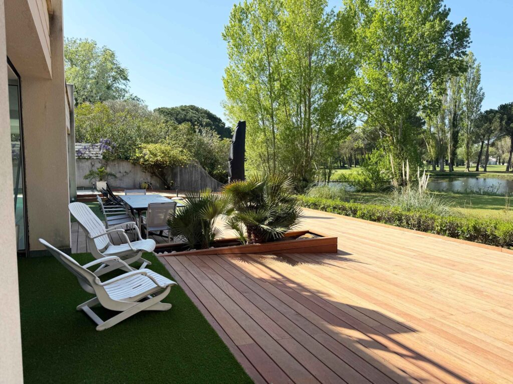 Vue de la terrasse en bois depuis la suite parentale, avec en fond l'étang du golf de la Grande Motte