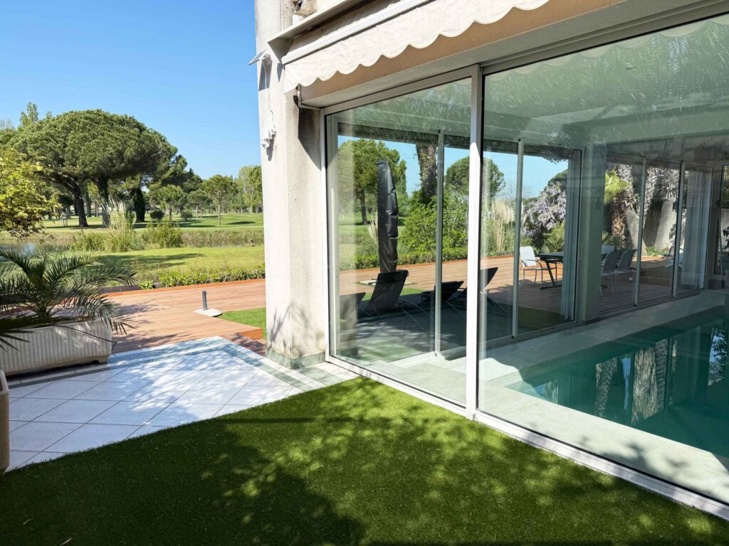 Photo de la piscine intérieure et terrasse en bois, devant le golf de la Grande Motte